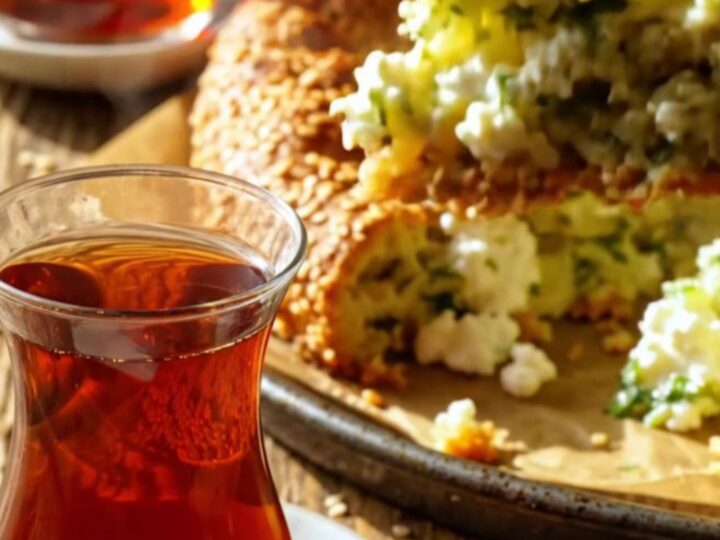 A golden-brown square slice of Turkish feta and dill cake with visible herbs and seeds, steam rising from it.