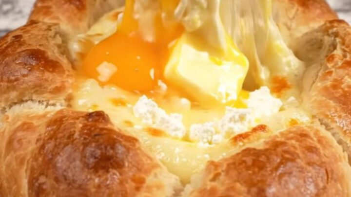A golden-brown Georgian cheese bread boat filled with molten mozzarella and feta cheese, topped with a raw