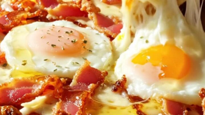 A golden cottage cheese flatbread pizza topped with melted mozzarella, crispy bacon, two baked eggs