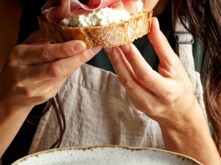 Close-up of a toasted sourdough slice topped with whipped ricotta, roasted figs, and prosciutto.