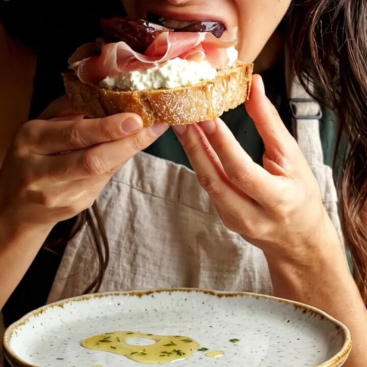 Close-up of a toasted sourdough slice topped with whipped ricotta, roasted figs, and prosciutto.