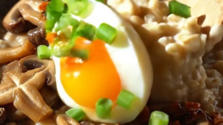 A bowl of savory oatmeal topped with sautéed shiitake mushrooms, a soft-boiled egg, and vibrant red chili crisp.