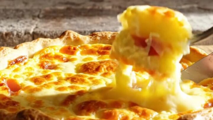 A golden-baked Quiche Lorraine with a visible, flaky crust and a rich, creamy filling, steaming on a rustic kitchen table.