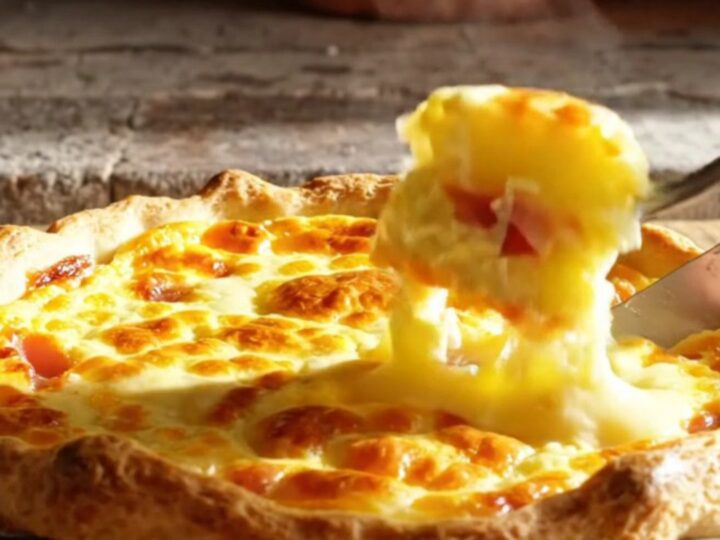 A golden-baked Quiche Lorraine with a visible, flaky crust and a rich, creamy filling, steaming on a rustic kitchen table.
