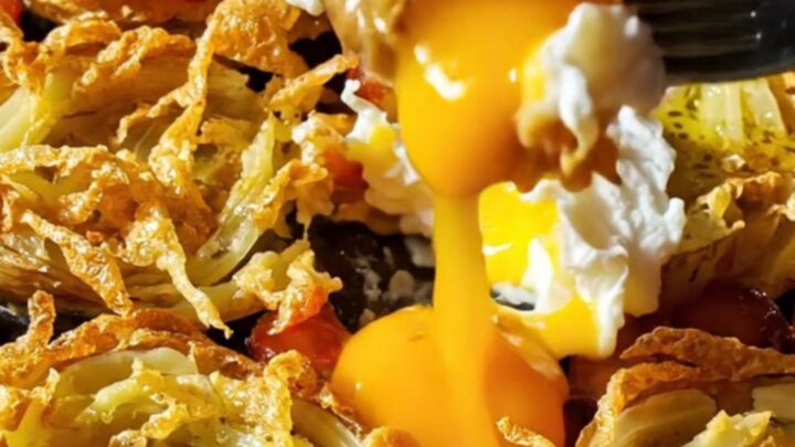 A close-up of crispy smashed fingerling potatoes topped with smoky chorizo and a poached egg with a runny yolk.