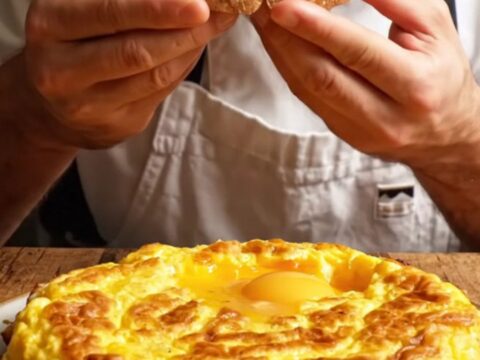 A thick, golden wedge of Spanish tortilla showing a creamy, custardy interior with tender potato slices.