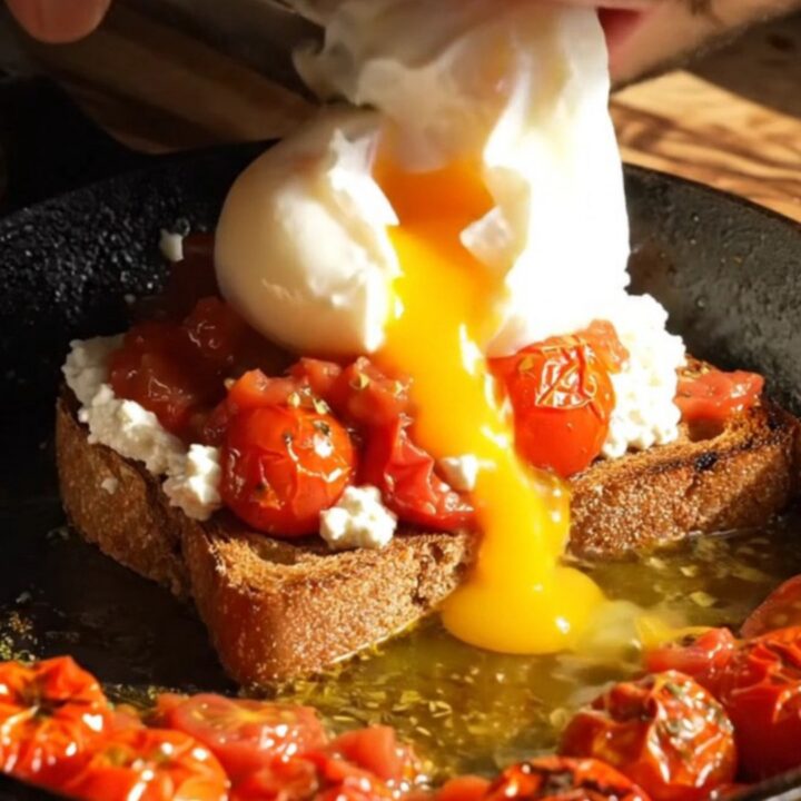 Vibrant whipped feta sourdough toast topped with blistered za'atar cherry tomatoes and a poached egg.