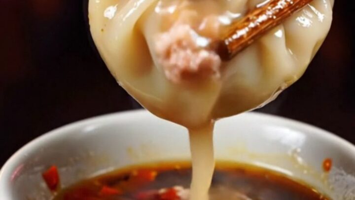 Golden crispy lace pork soup dumplings served on a dark plate with chili oil.