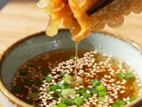 A close-up of a crispy rice paper dumpling split in half, revealing a savory tofu and glass noodle filling.
