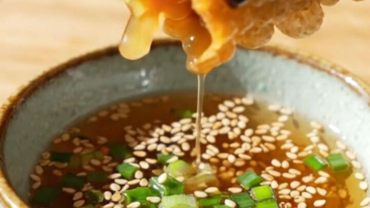 A close-up of a crispy rice paper dumpling split in half, revealing a savory tofu and glass noodle filling.