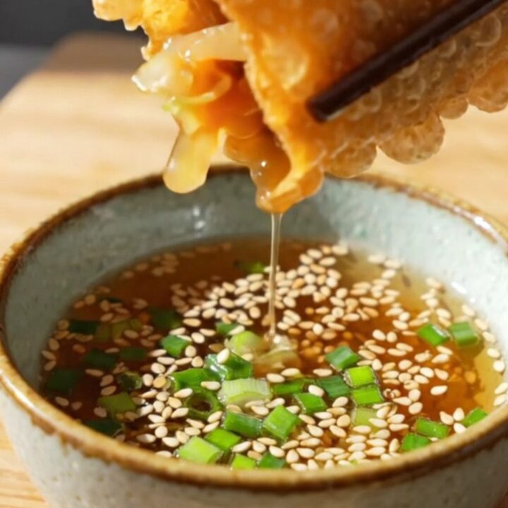 A close-up of a crispy rice paper dumpling split in half, revealing a savory tofu and glass noodle filling.