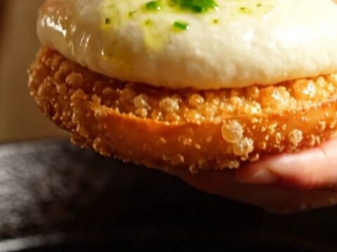 Golden pan-seared chicken and shiitake baozi torn open showing steaming savory filling and crispy base.
