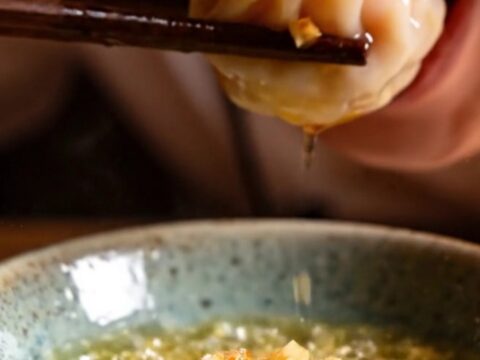 A close-up shot of crystal shrimp dumplings topped with vibrant, sizzling garlic chili crisp.