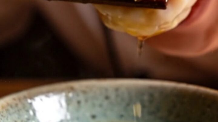 A close-up shot of crystal shrimp dumplings topped with vibrant, sizzling garlic chili crisp.