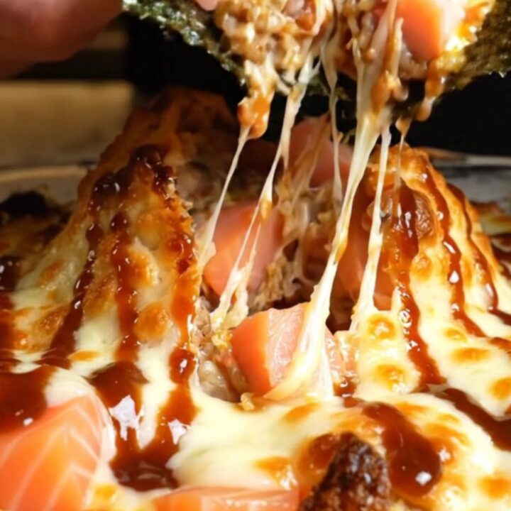 A vibrant volcano salmon sushi bake in a baking dish with golden, bubbling cheese peaks and colorful garnishes.