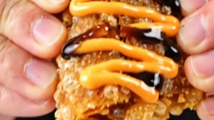 A crispy folded sushi wrap drizzled with spicy mayo and eel sauce, showing flaky salmon and avocado.