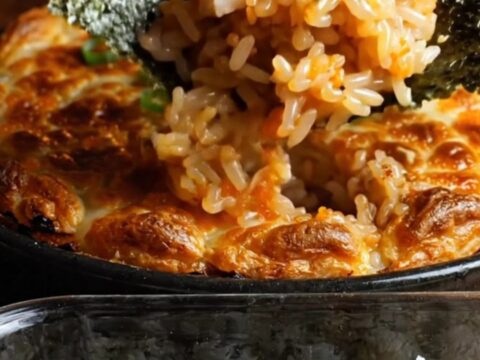 A close-up shot of a creamy dynamite kani crab sushi bake in a baking dish
