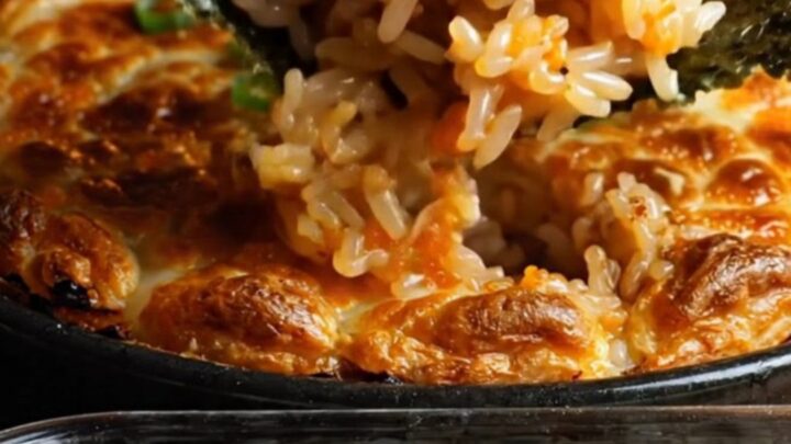 A close-up shot of a creamy dynamite kani crab sushi bake in a baking dish