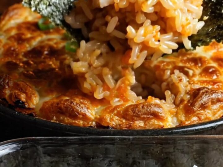 A close-up shot of a creamy dynamite kani crab sushi bake in a baking dish