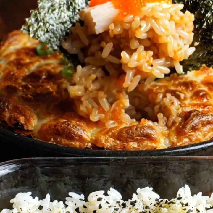 A close-up shot of a creamy dynamite kani crab sushi bake in a baking dish