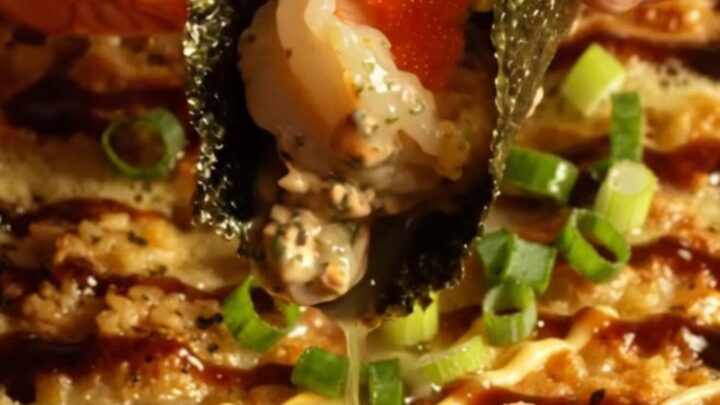 A close-up of a creamy garlic butter shrimp sushi bake in a ceramic dish, topped with scallions and masago.