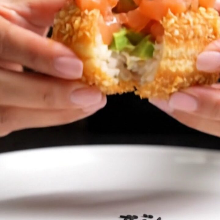 A golden-fried sushi rice donut topped with spicy salmon tartare, avocado roses, and a drizzle of eel sauce.