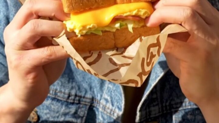 A close-up shot of a buttery, golden-brown Korean street toast sandwich sliced diagonally.