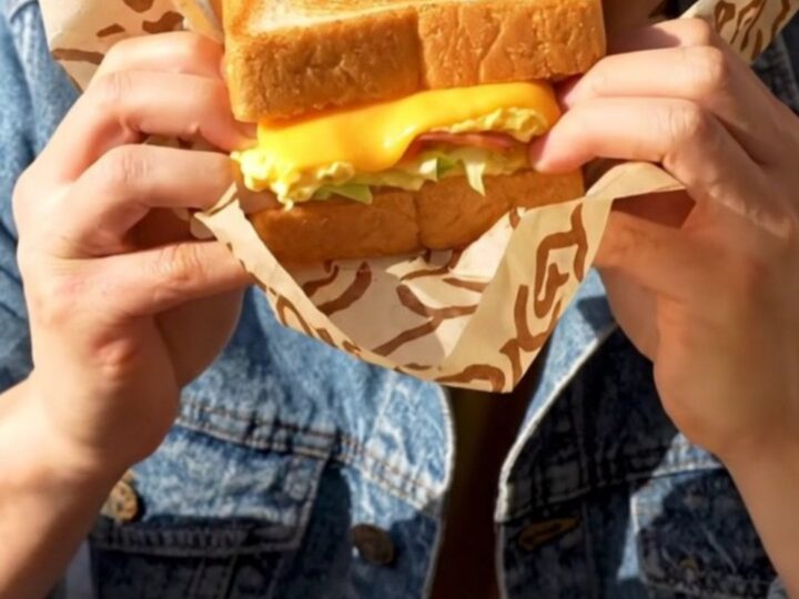 A close-up shot of a buttery, golden-brown Korean street toast sandwich sliced diagonally.