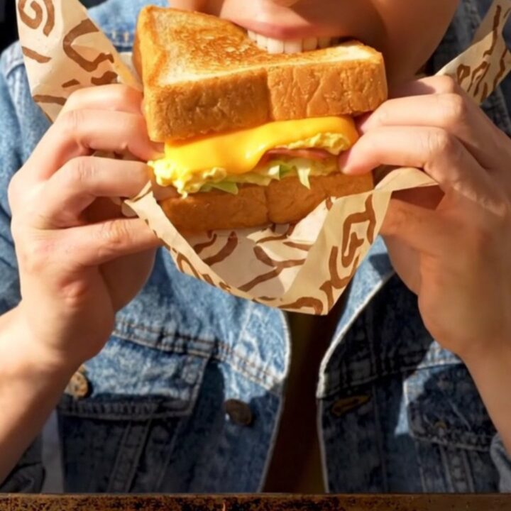 A close-up shot of a buttery, golden-brown Korean street toast sandwich sliced diagonally.