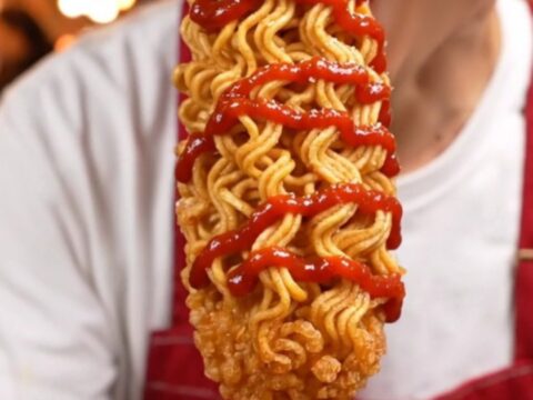 A golden, ultra-crispy ramen-crusted Korean cheese corn dog showing a molten cheese center.