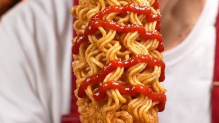A golden, ultra-crispy ramen-crusted Korean cheese corn dog showing a molten cheese center.