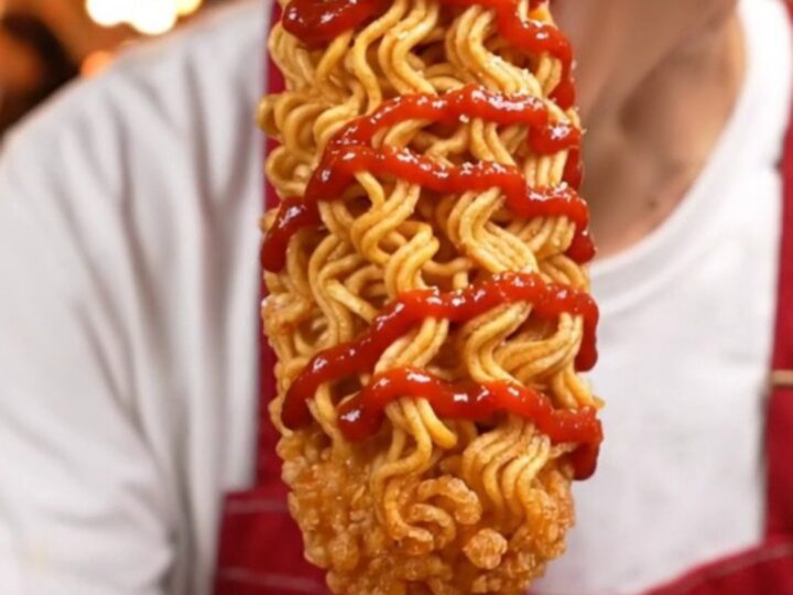 A golden, ultra-crispy ramen-crusted Korean cheese corn dog showing a molten cheese center.