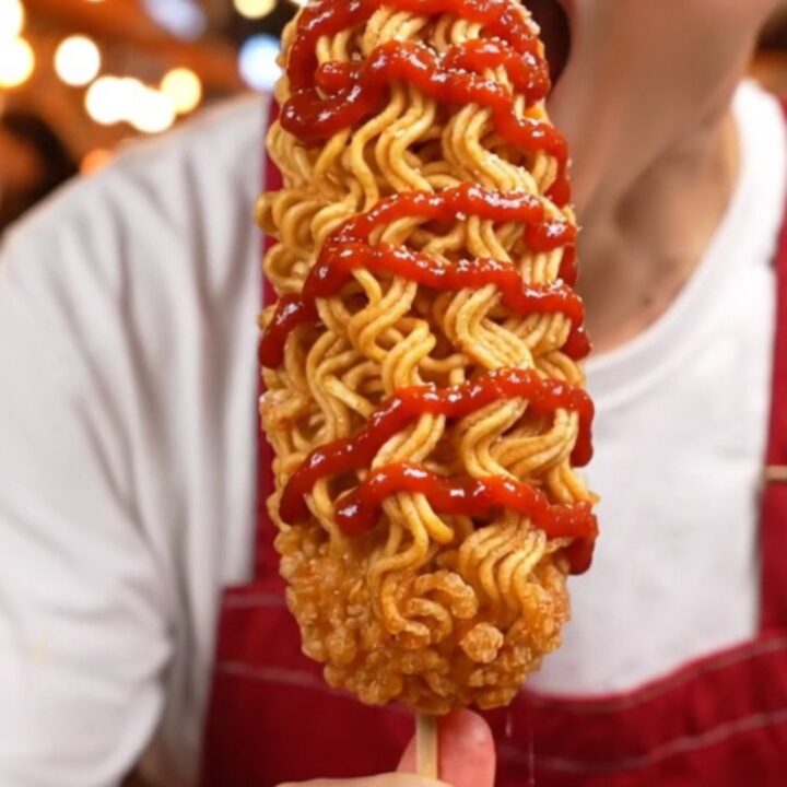 A golden, ultra-crispy ramen-crusted Korean cheese corn dog showing a molten cheese center.