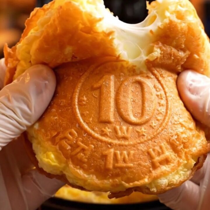 A golden, coin-shaped pancake split in half showing a long, stretchy pull of melted mozzarella cheese.