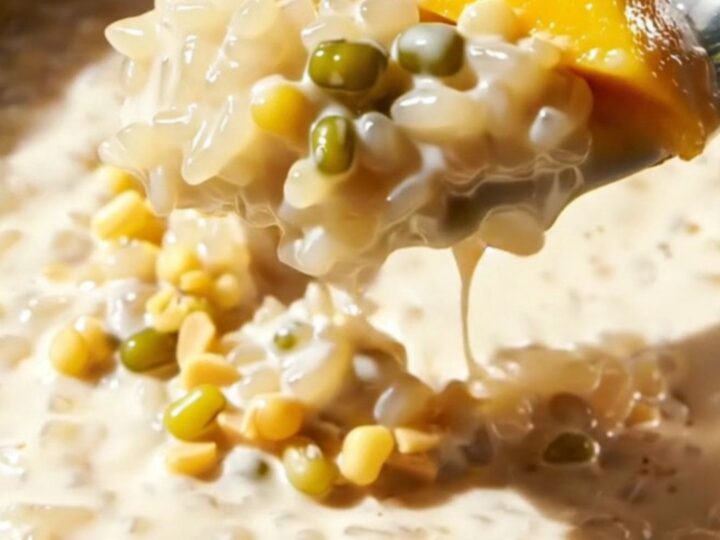Close up of creamy Thai mango sticky rice topped with crunchy mung beans on a plate.