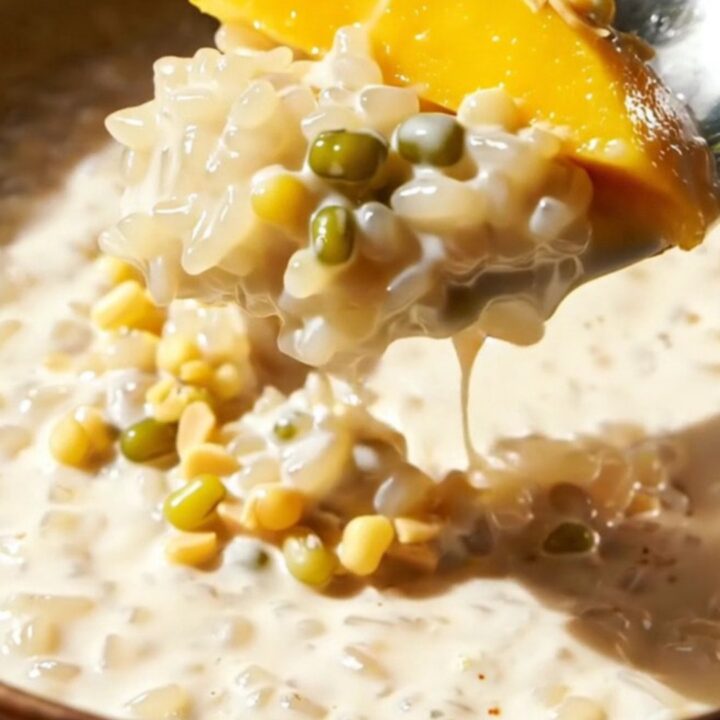 Close up of creamy Thai mango sticky rice topped with crunchy mung beans on a plate.