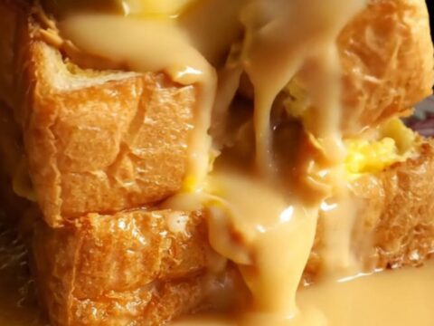 A close-up shot of golden-brown Hong Kong French toast with peanut butter oozing from the center.