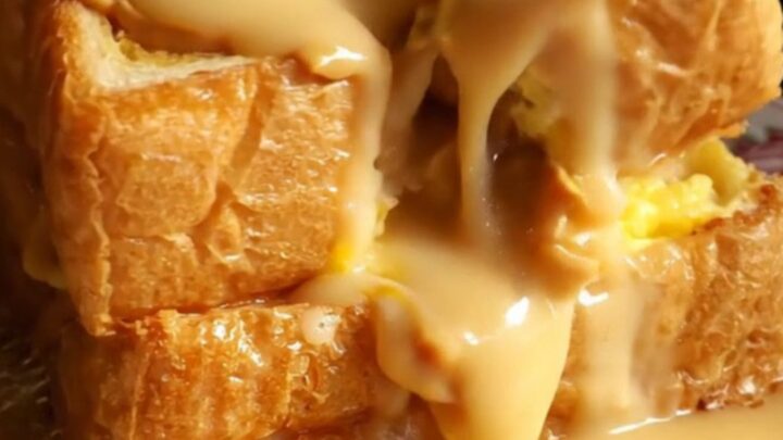 A close-up shot of golden-brown Hong Kong French toast with peanut butter oozing from the center.