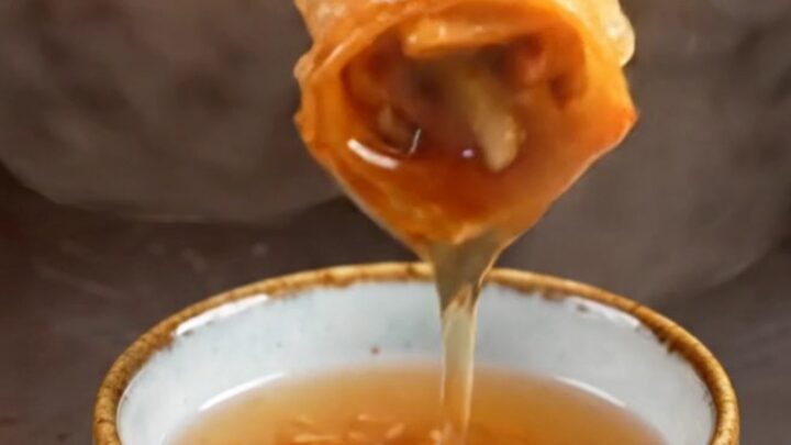 A close-up shot of golden-fried Peking duck spring rolls with a shattered, crispy texture.