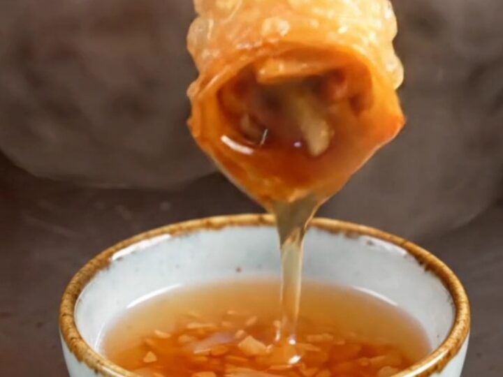 A close-up shot of golden-fried Peking duck spring rolls with a shattered, crispy texture.