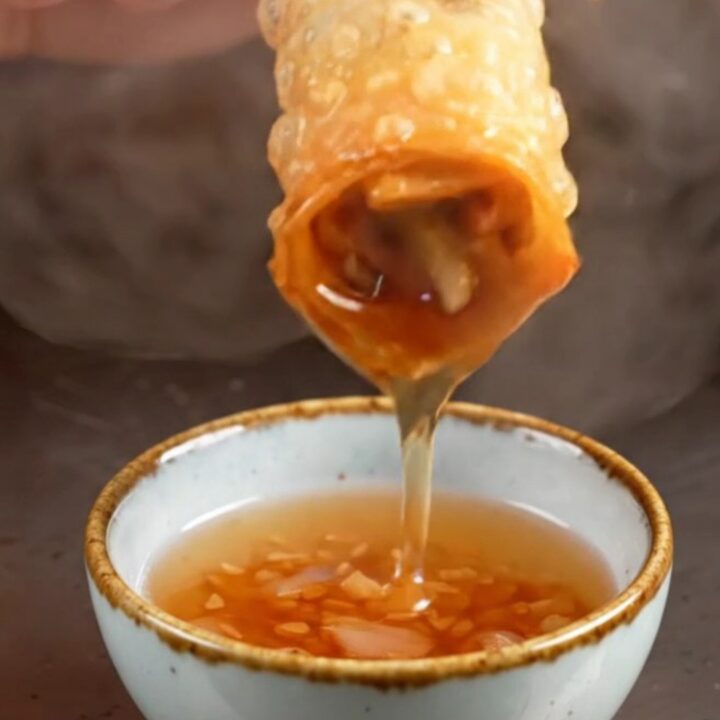 A close-up shot of golden-fried Peking duck spring rolls with a shattered, crispy texture.