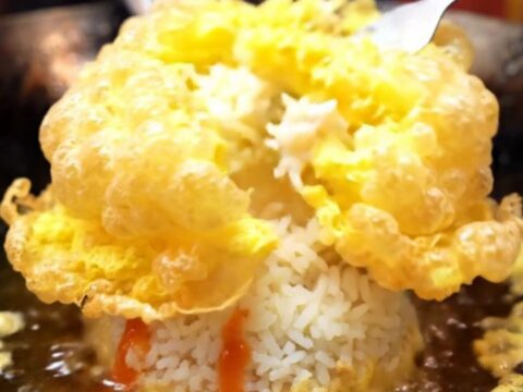 A golden, crispy Thai omelet with lacy edges served over steaming jasmine rice with sriracha.
