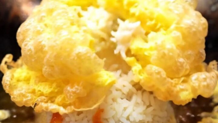 A golden, crispy Thai omelet with lacy edges served over steaming jasmine rice with sriracha.