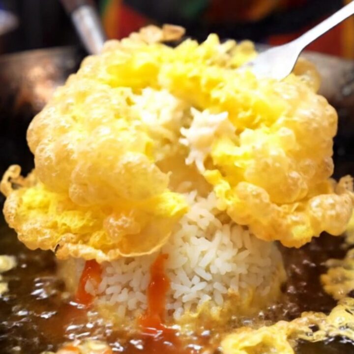 A golden, crispy Thai omelet with lacy edges served over steaming jasmine rice with sriracha.