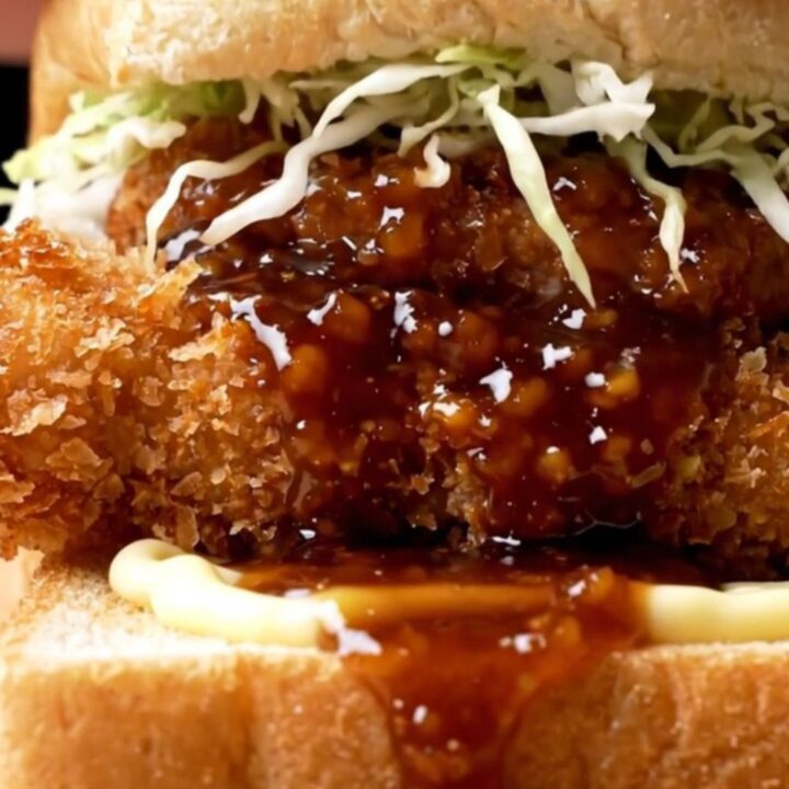 A close-up view of a crispy chicken katsu sando on shokupan bread, showcasing the golden panko crust and fresh cabbage.
