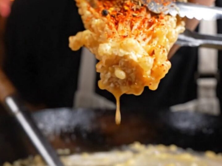 A golden, crispy cluster of fried enoki mushrooms dusted with vibrant red Sichuan mala spices.
