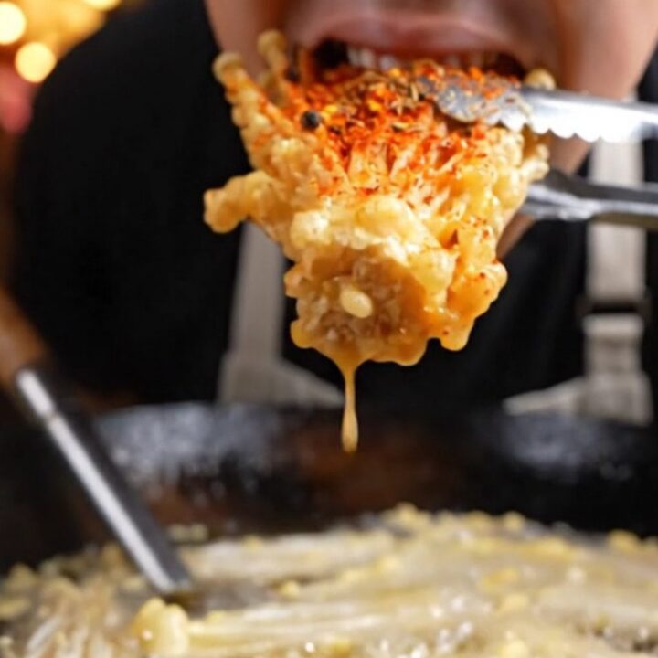 A golden, crispy cluster of fried enoki mushrooms dusted with vibrant red Sichuan mala spices.