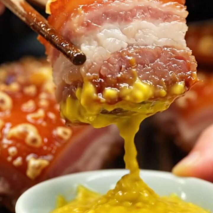 A golden-brown Cantonese roast pork belly slab with perfectly blistered, crispy skin on a wooden board.