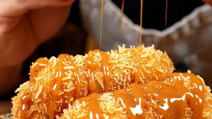 A close-up of a golden-brown banana turon split in half, showing the steaming banana and jackfruit filling with a crackling