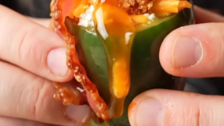 A close-up shot of crispy bacon-wrapped jalapeño poppers with bubbling cheese filling.